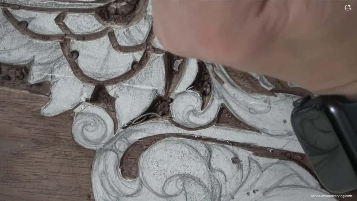 Carved leaves running into one another, his forearm crossing the top of the frame, chalk everywhere.