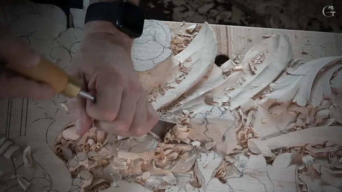 Yellow handled gouge held in two hands over the leaves