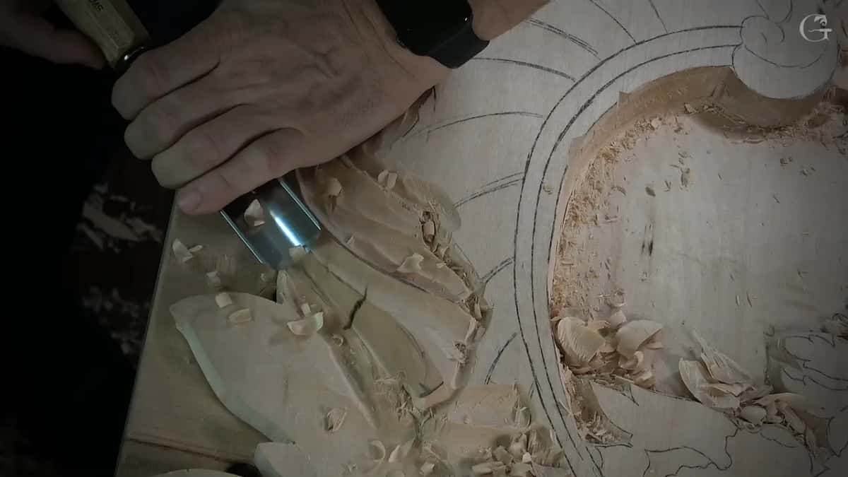 Knuckles wrapped over the handle as the wide gouge scoops into the shape