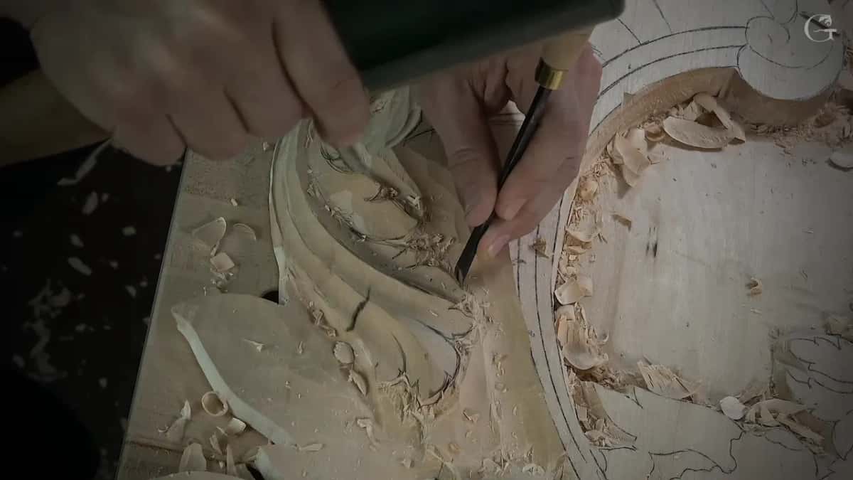 A green mallet head at the top of the picture while a narrow gouge stands upright at the outline