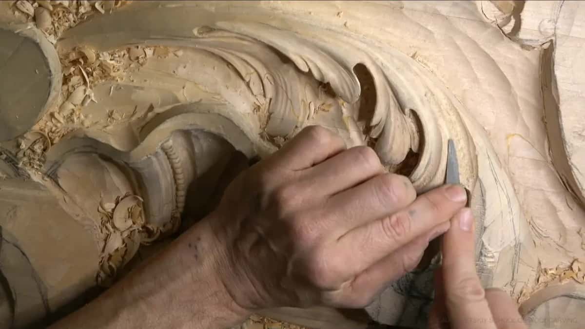 Rasp working the tight inner curve of one acanthus lobe, beside pencil lines still visible.