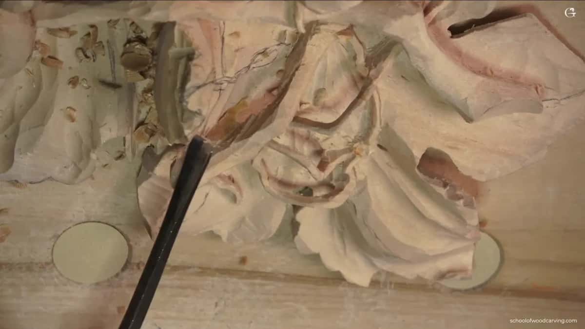 A tool reaching in under a carved leaf, where a hollow is being taken out for shadow
