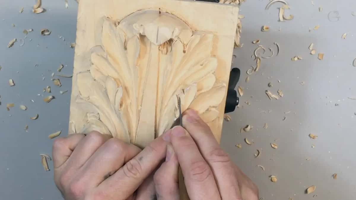 Knife work along the outline, both thumbs steadying the blade close to the edge