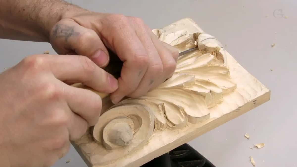Tattooed forearm and both hands working the top of the curl
