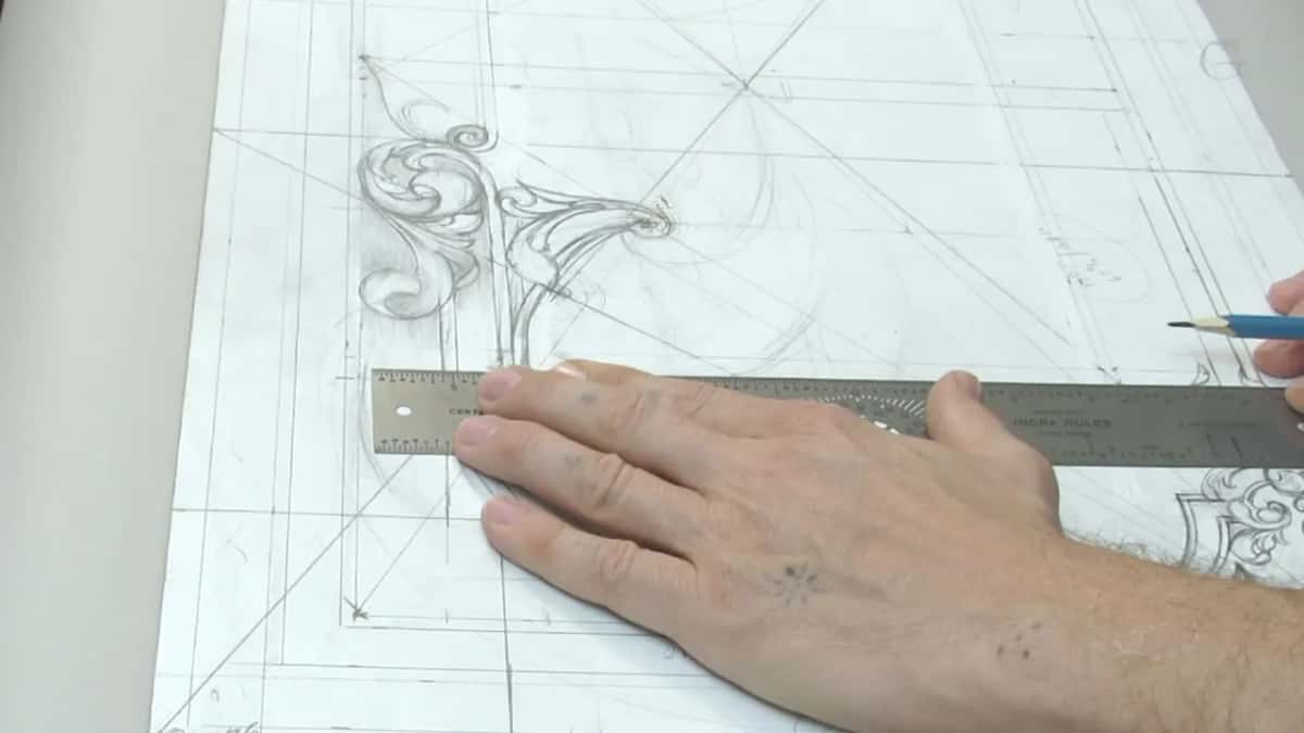 Long steel rule lying across the drawing, blue pencil in the right hand, left hand holding it steady