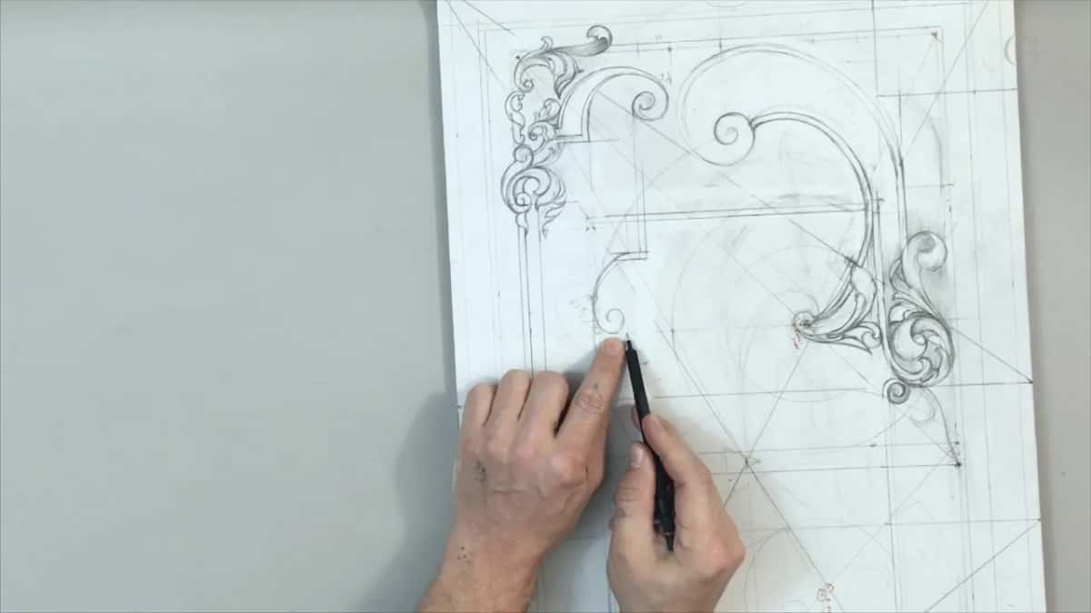 Black pencil curling a small volute, the left hand steadying the sheet beside it