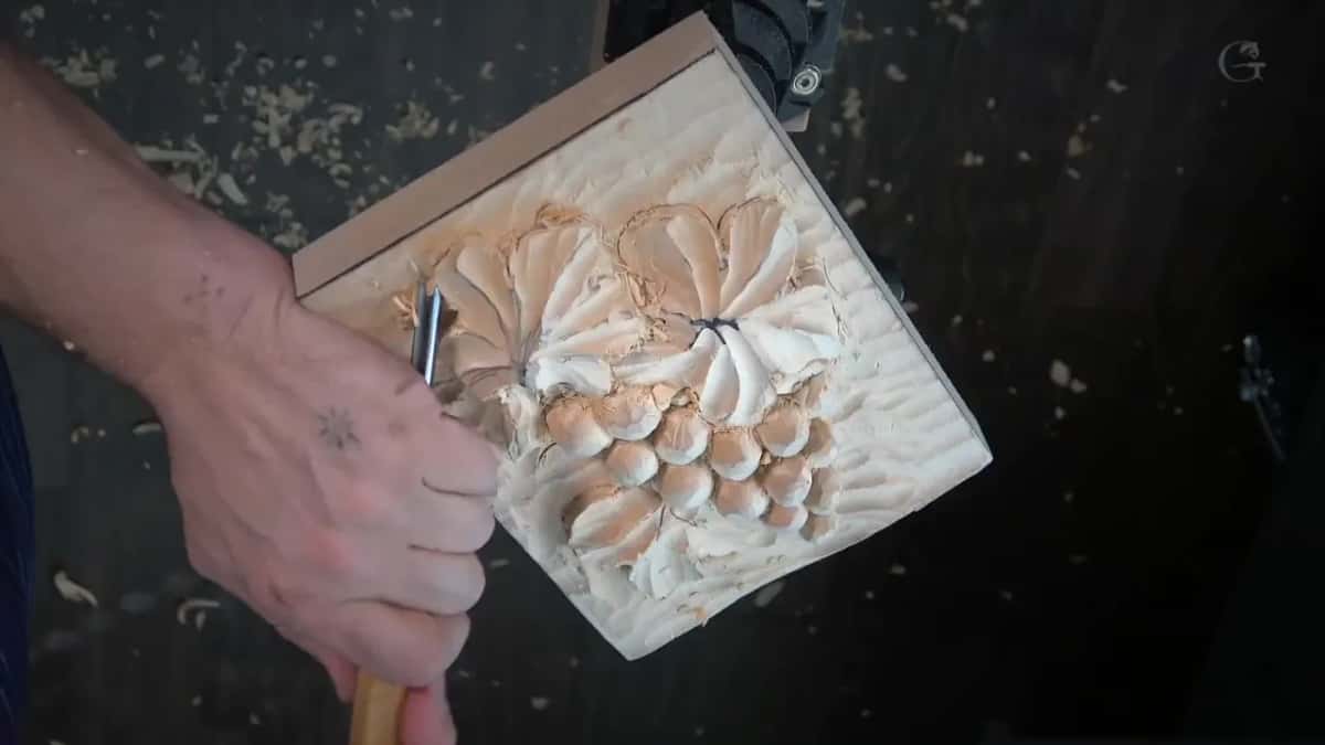 Gouge against a half carved cluster, chips across the dark bench.