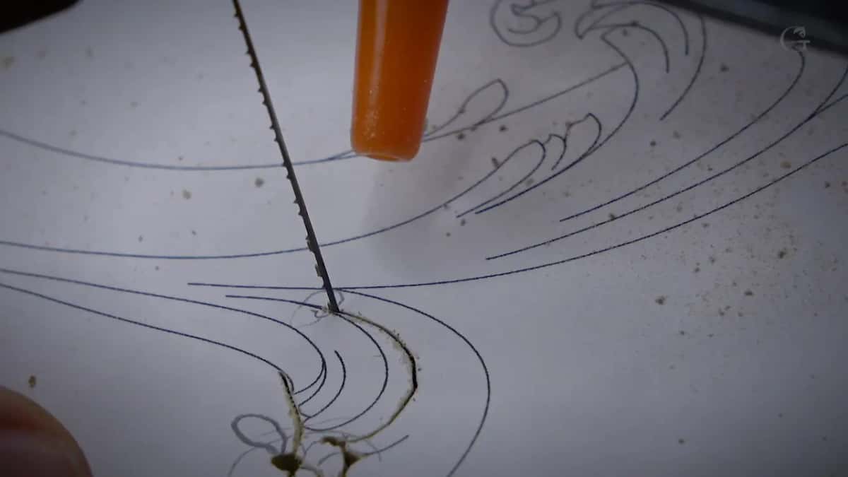 Following the line Fingertip at the lower left keeps the board still while the blade tracks one printed line around a curve