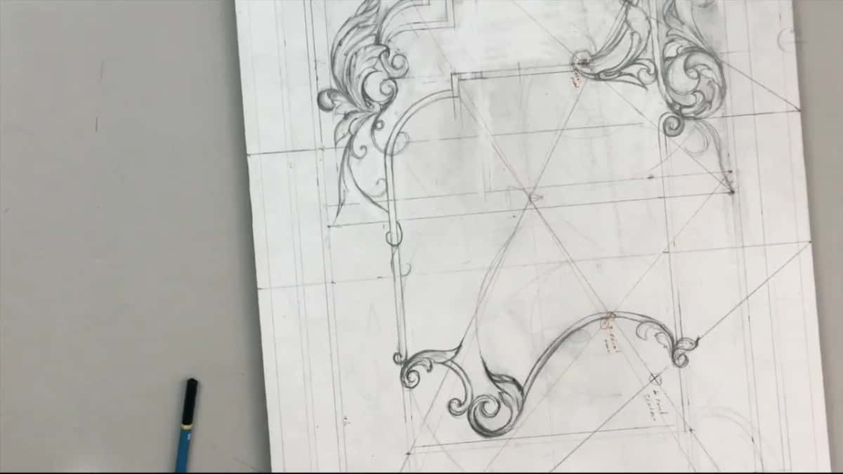 Board at an angle, its lower ornament now developed, a blue pencil lying beside it