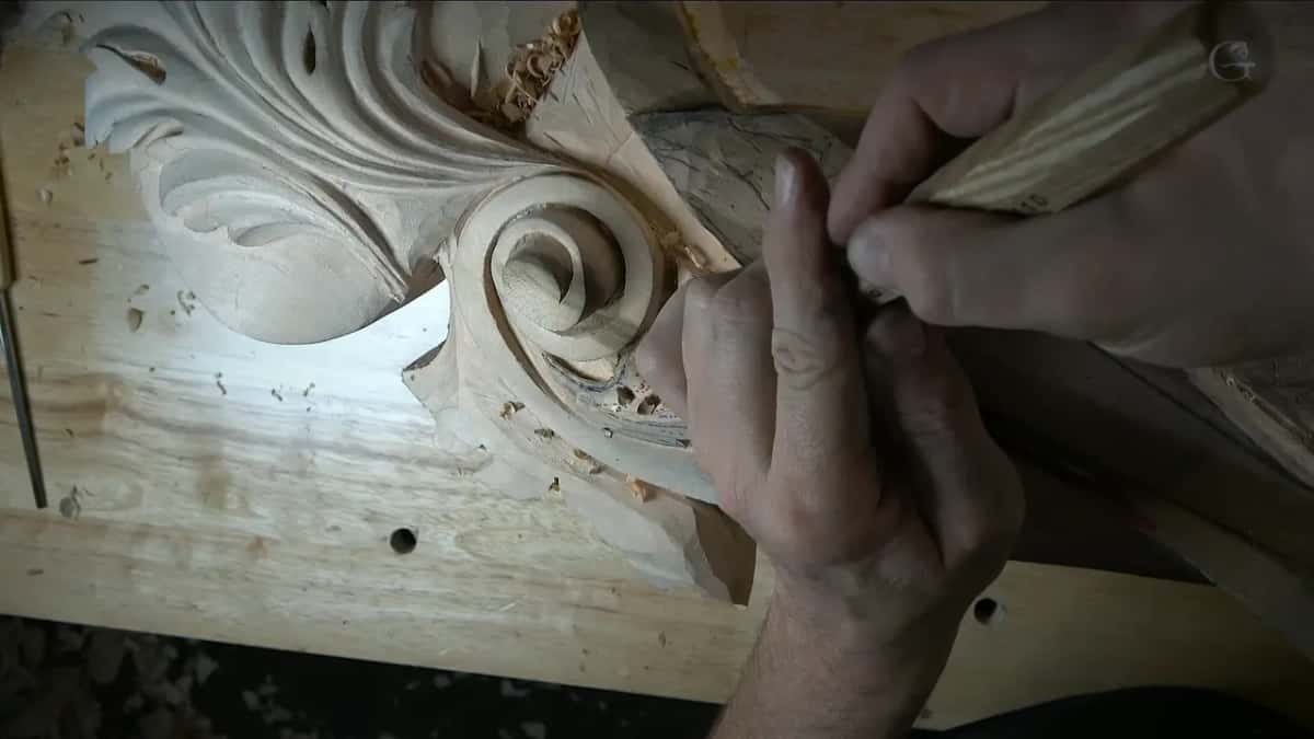 Close view, a thumb pressed on the blade, the spiral of the volute right past the steel edge