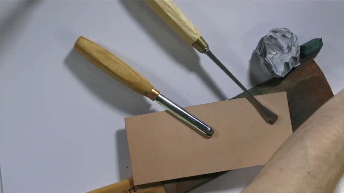 Two gouges resting on bare leather beside a grey block