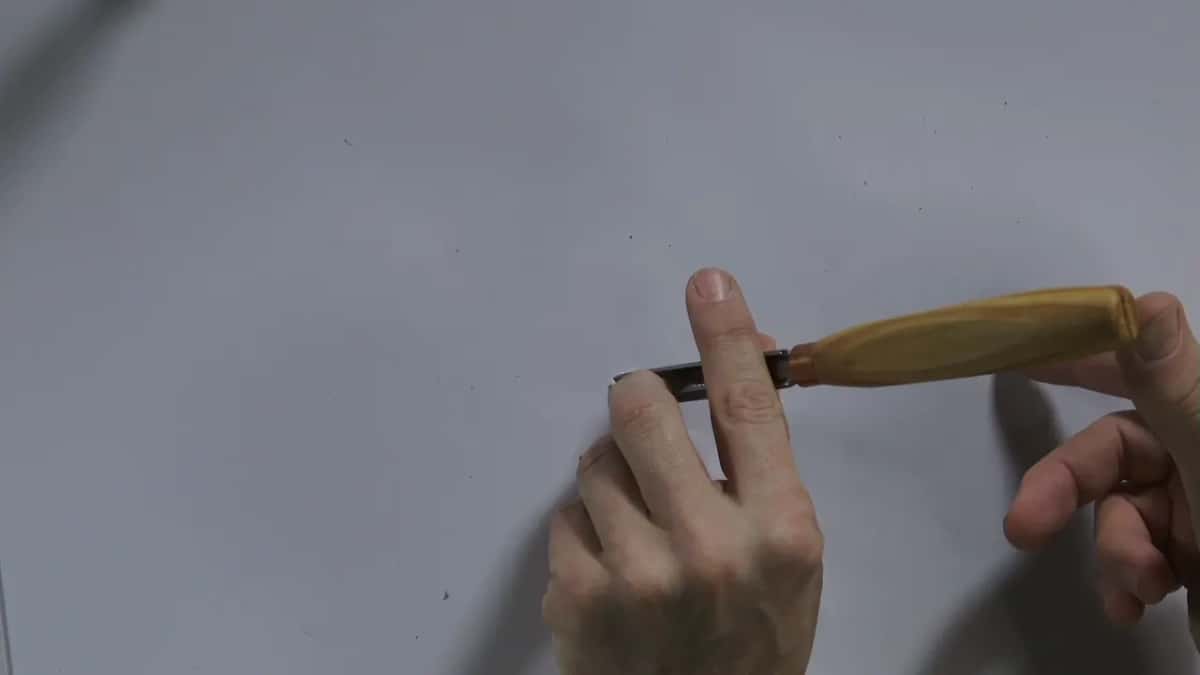Gouge laid flat, a finger beneath the blade, handle held low