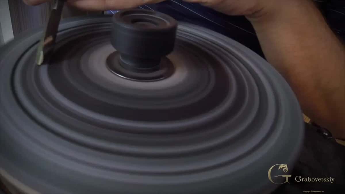 Held by hand, the blade rests on a grey wheel turning in rings.