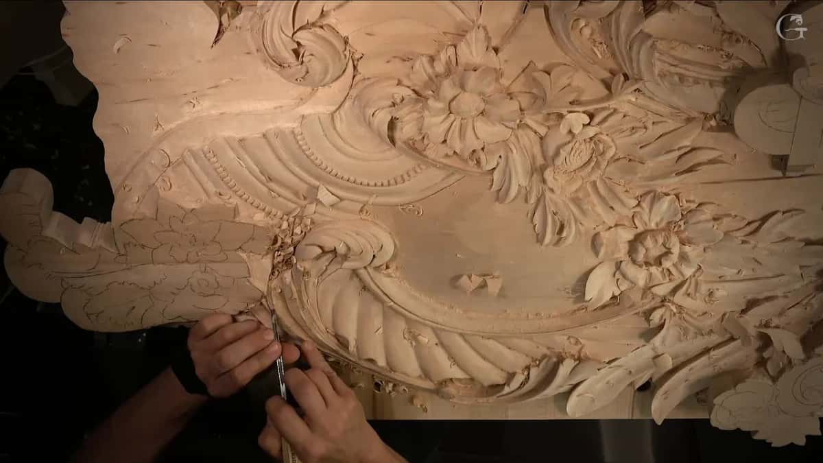Fingers pinching a small tool on the curled end of the shell, the flowers higher up