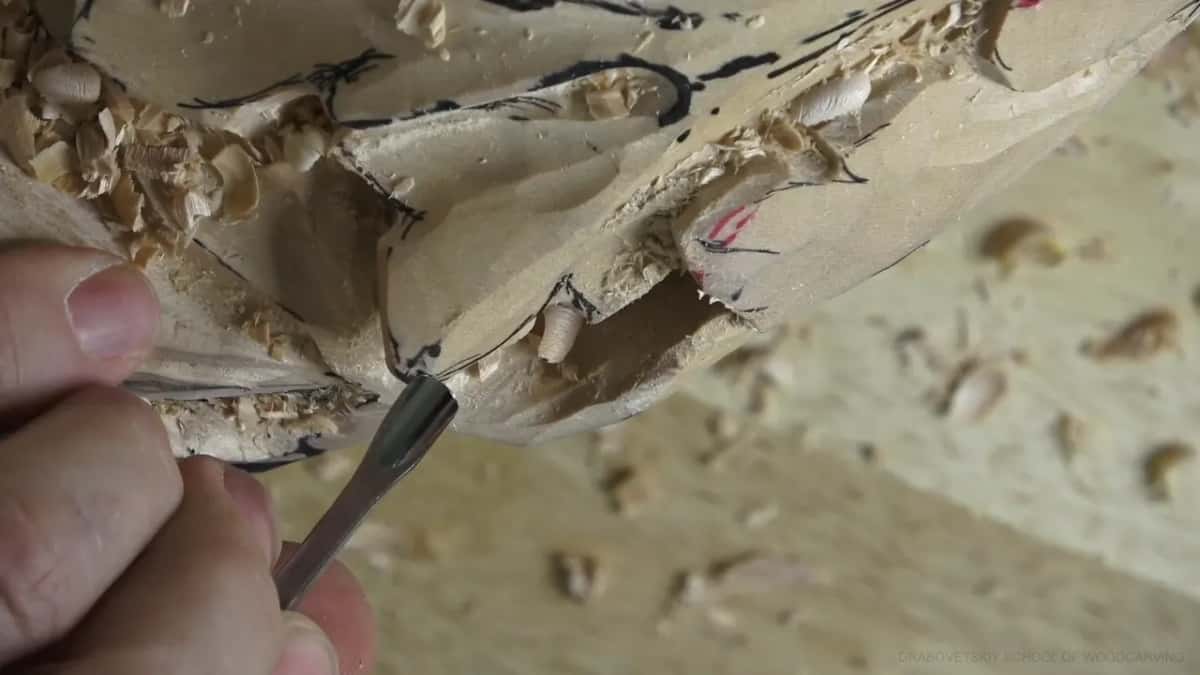 Blade flipped over Thumb and finger steady a slim curved blade going in under a leaf edge