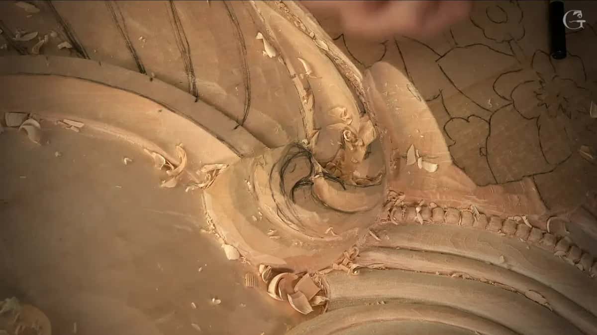 A hand lifts away from the scroll, its pencilled spiral still showing