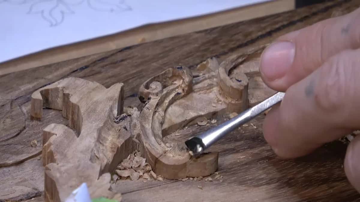 Flat gouge taking the scroll's end down toward the lid, a paper drawing of the design behind