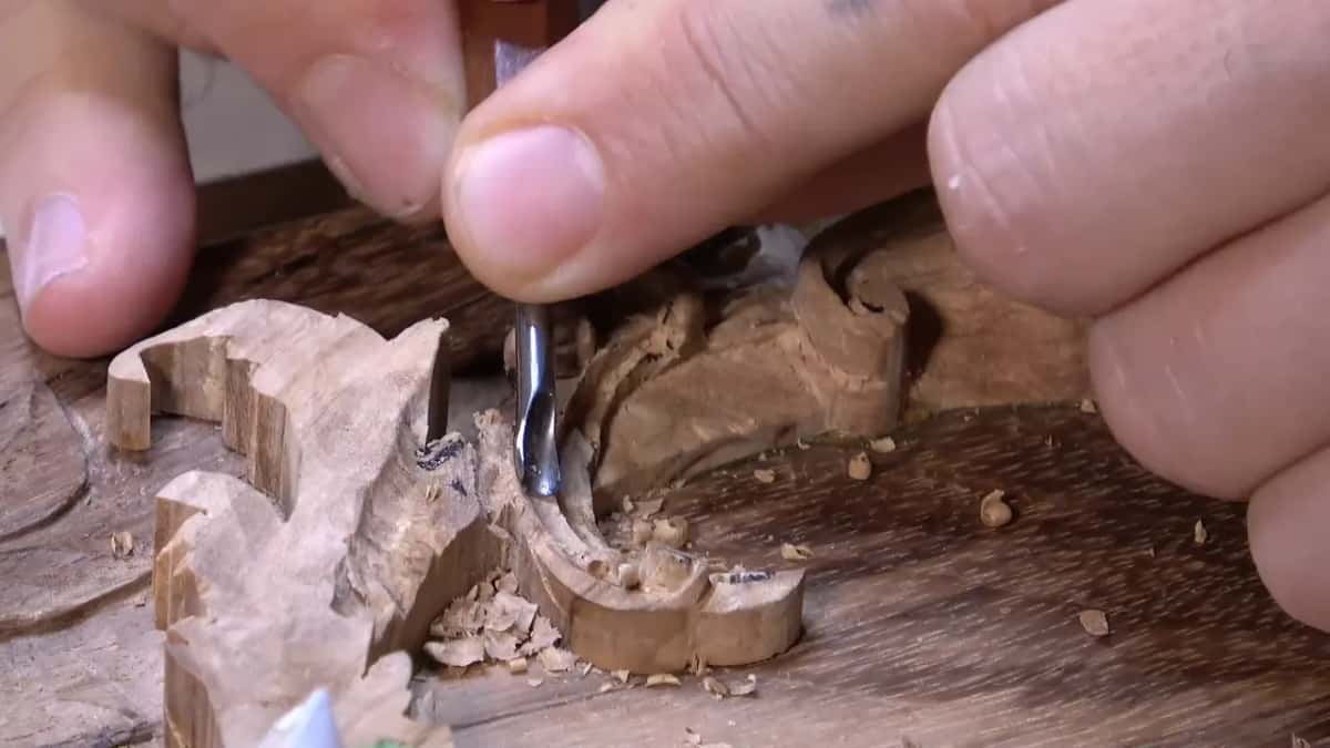 Side view of a small gouge scooping a low hollow beside the sawn wall