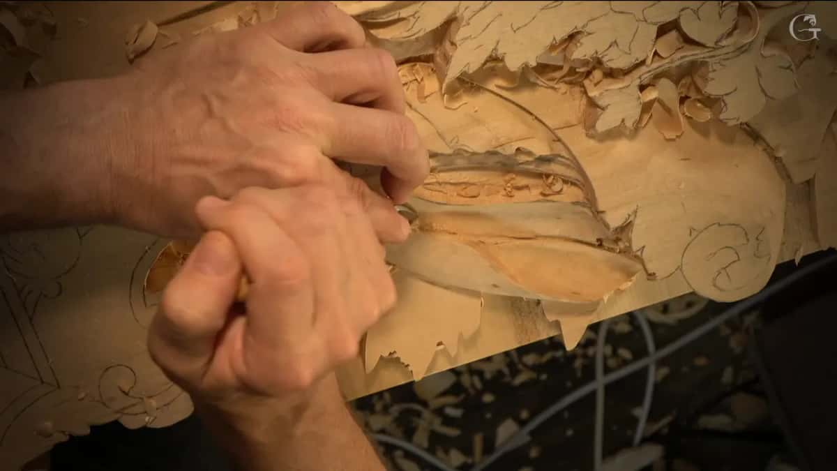 Knuckles close to the wood as one hand presses the other, pushing a tool into the hollow