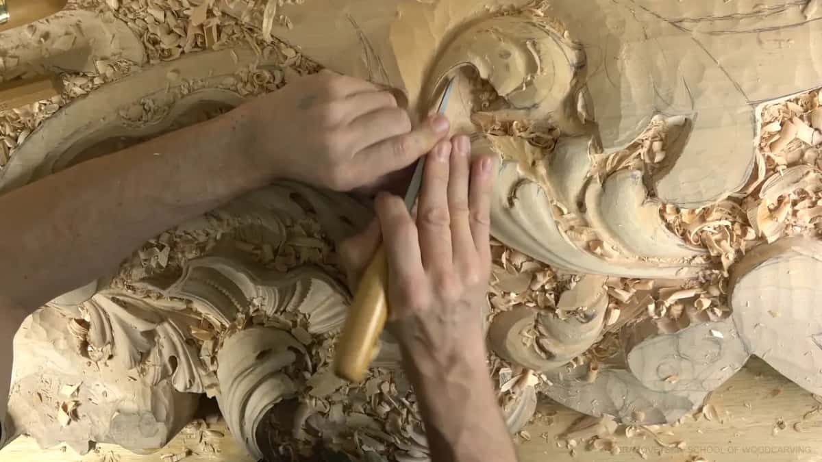 Both hands steady one small gouge at the rim of the round shape.