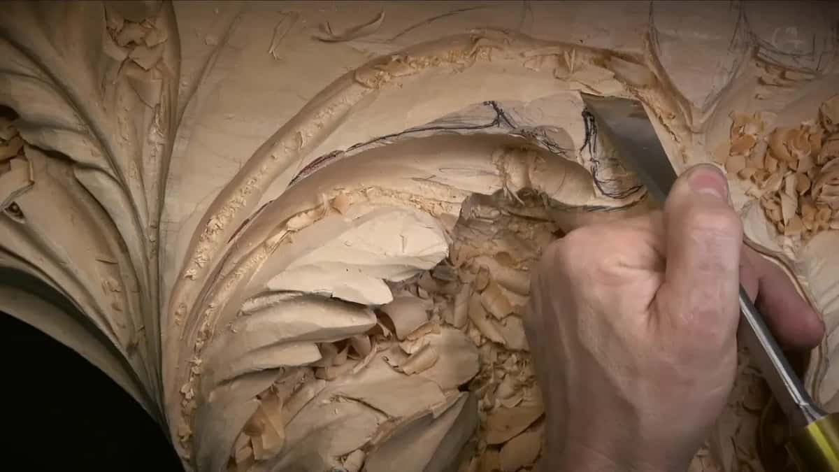 Narrow straight edge held at a slant along the curled lobe, red lines marking the rim