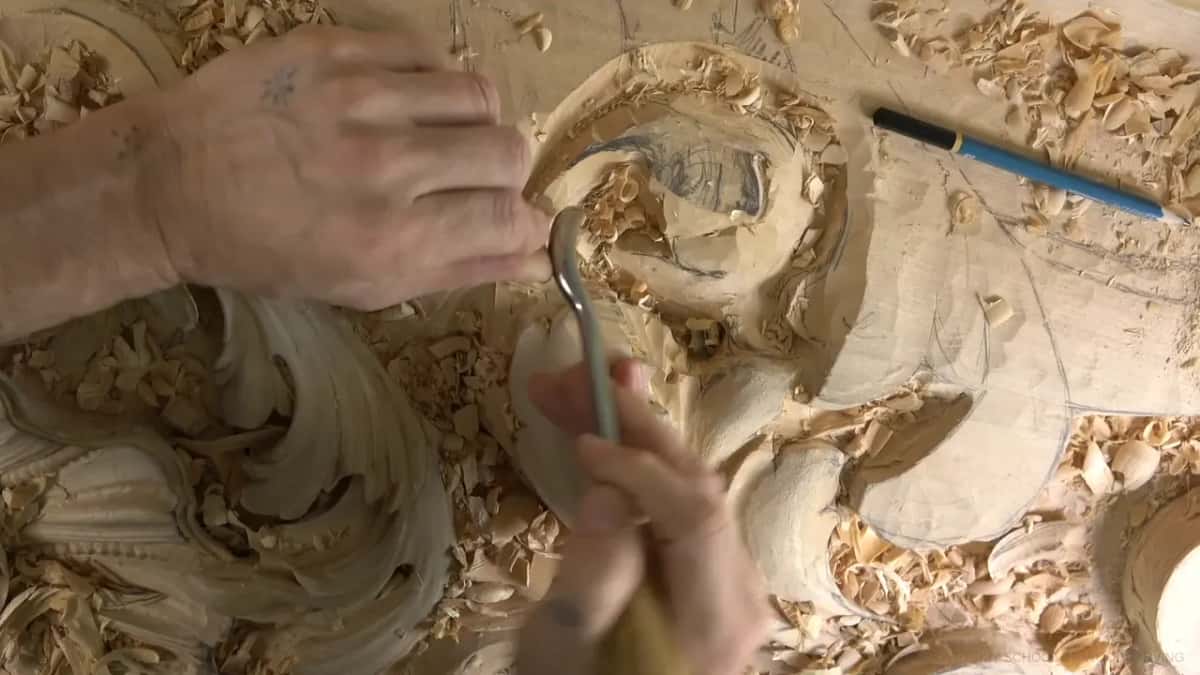 Bent spoon gouge dipping into the pocket, one hand on its shank and the other on the handle.