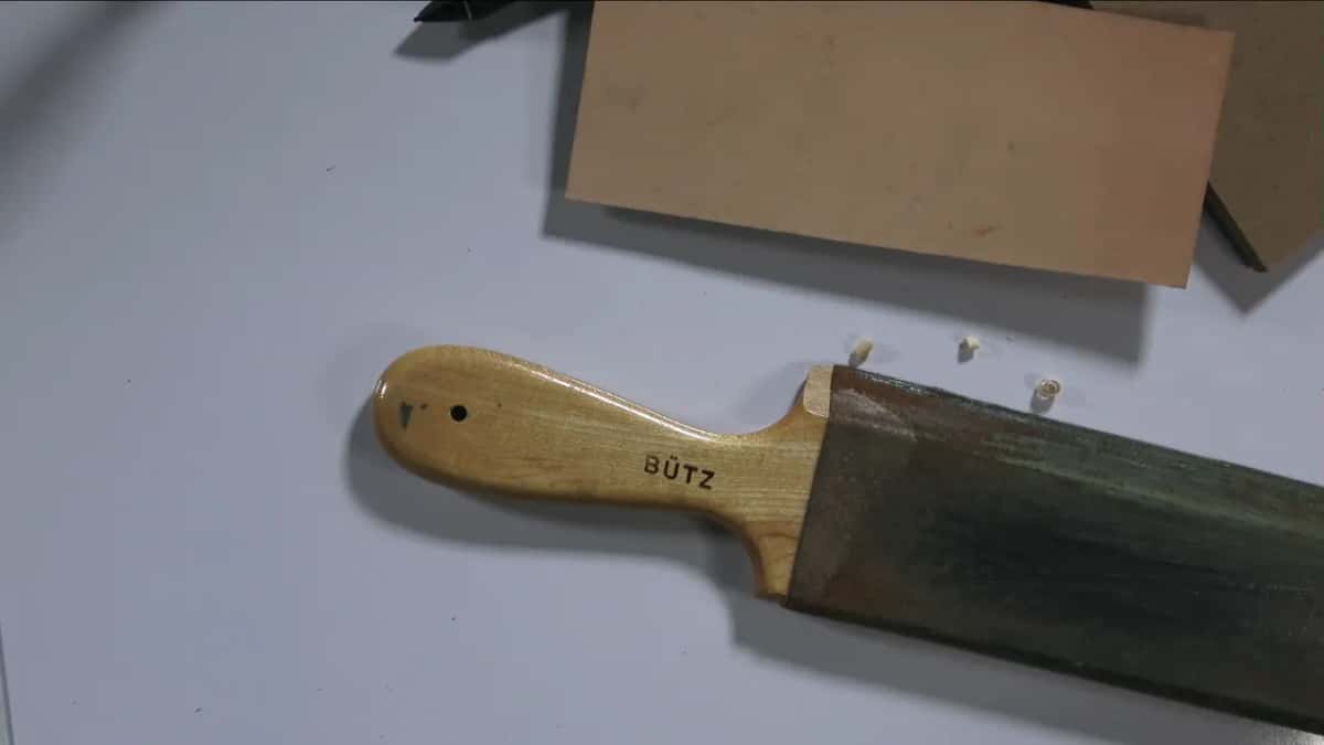 Stropper with a pale handle stamped BUTZ, its leather face worn dark green.