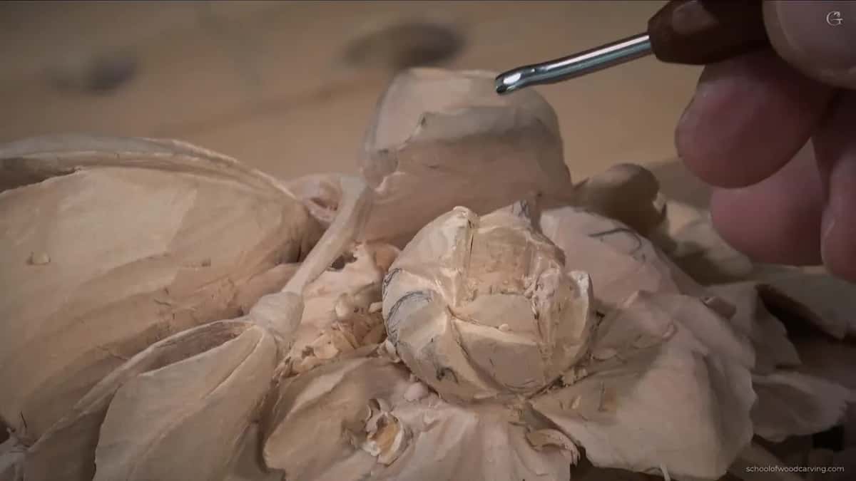 Held above the swirl, a gouge with its bright steel sweep turned toward the camera