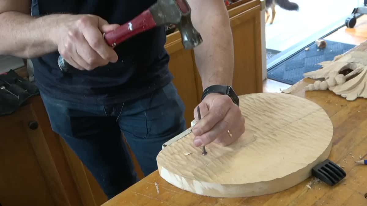 Nail held clear of the surface with the hammer coming down on it