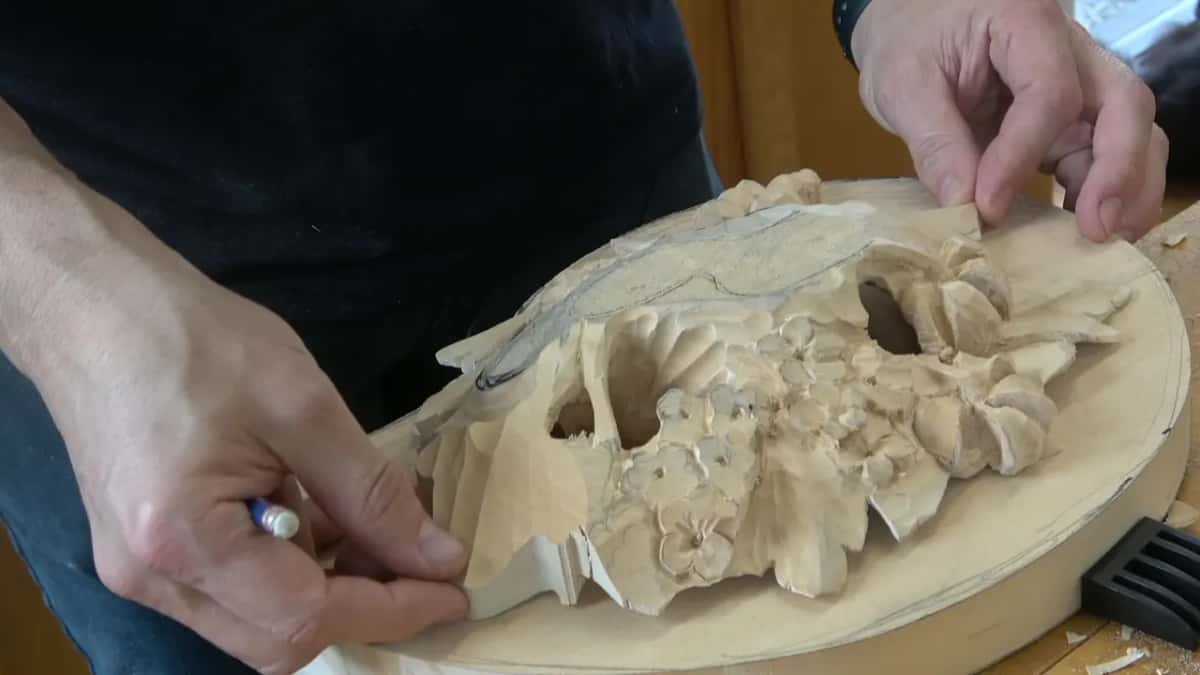 The carved layer lowered onto its shaped ground board, hands holding it in position