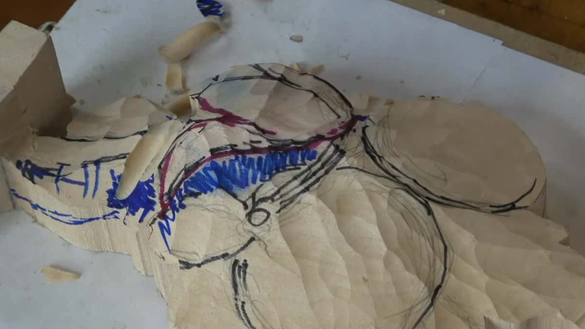 Red and blue ink sitting in the grain while a shaving curls off beside it