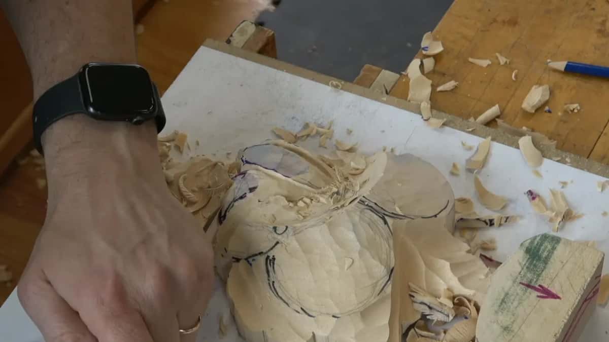 Wide view of the whole blank, tulip roughed round, leaves still square at the edges, drawing board propped at the right