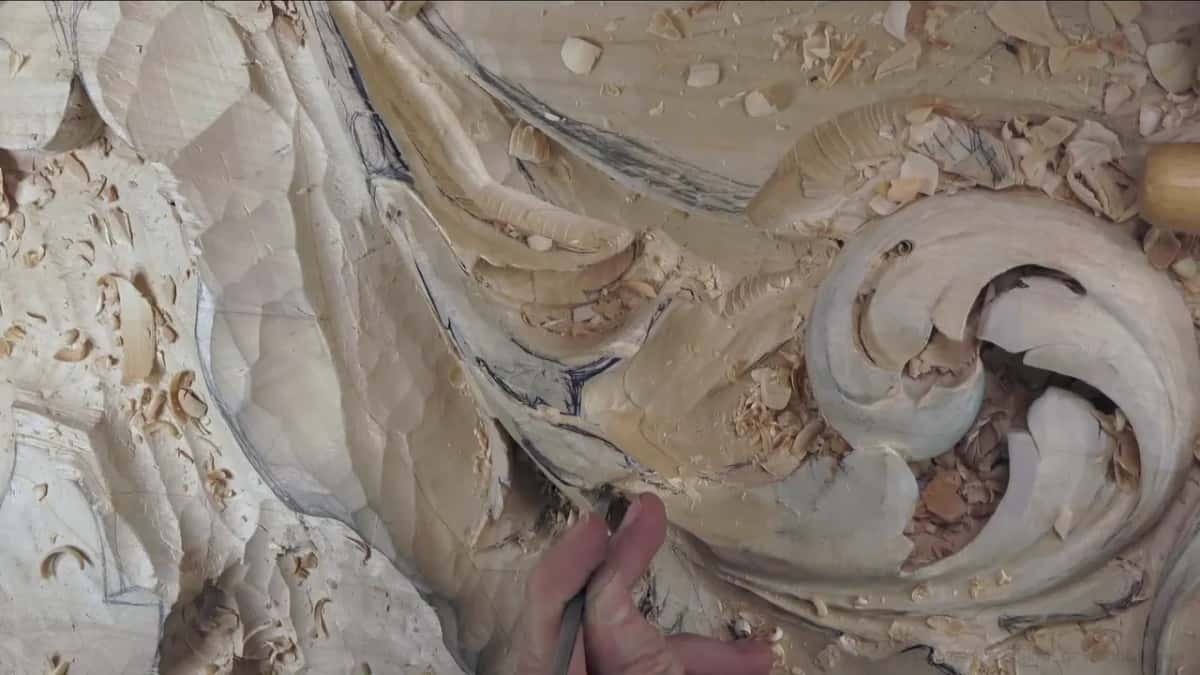 Held low beside a separation on the lower lobe, a thin tool, chips scattered around the curl.