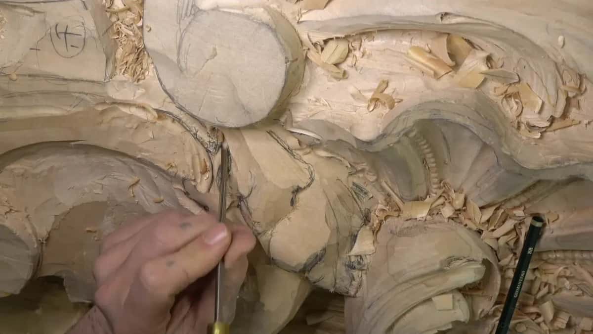 A thin tool reaches down into a narrow hollow while a pencil lies off to the right.