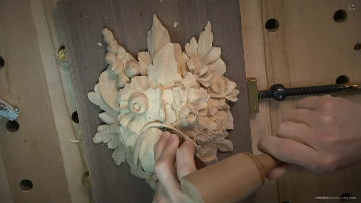 Both hands guiding a Peter Benson detailing tool along the stem of the tulip on the Grinling Gibbons panel
