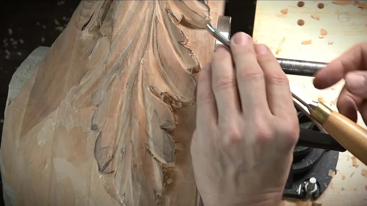 Close view of a tool at the lobe edge, pale handle, bench holes behind