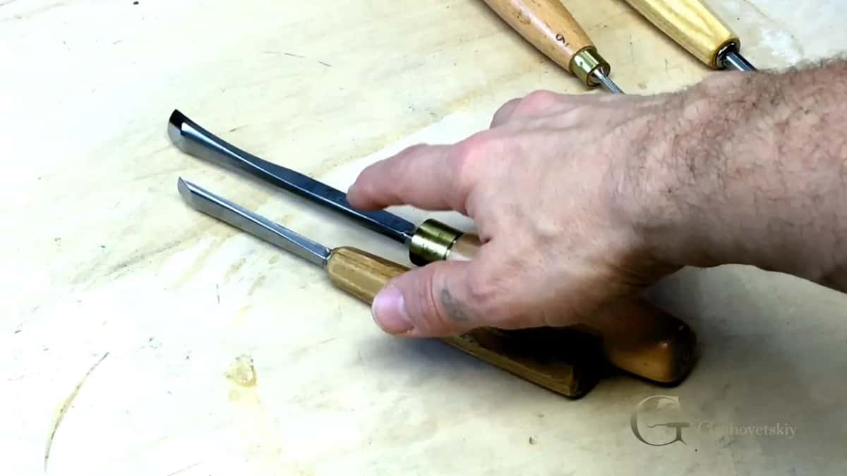 Hand resting beside two tools.