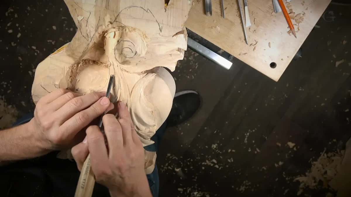 Both hands steering a narrow gouge into the leaf
