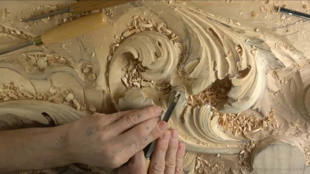 Two hands on a small gouge inside one curling lobe.