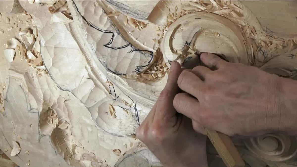 Both hands close together on a small tool at the top of the scroll.