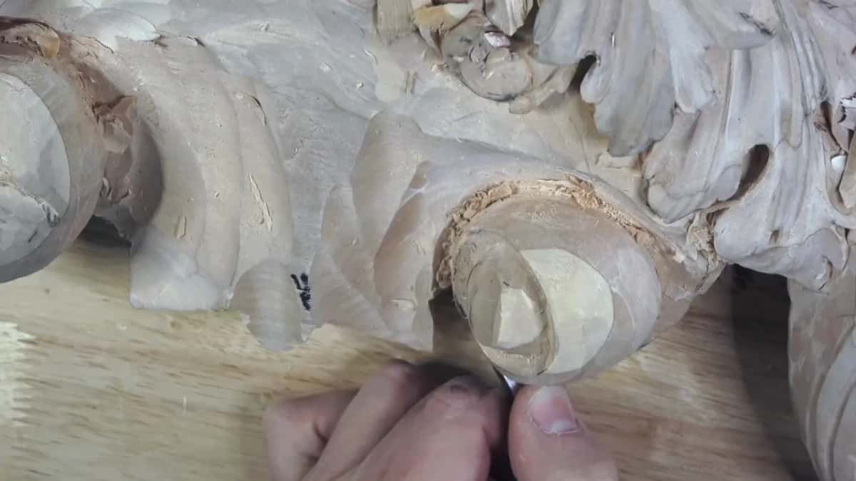 The barrel end Fingers steering a bent tool into the rounded end of the volute barrel, cut like a drum lifted clear of the ground