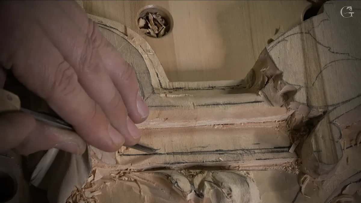 Hand guiding a very small veiner along a dark pencil line on the band, chips in a bench dog hole above