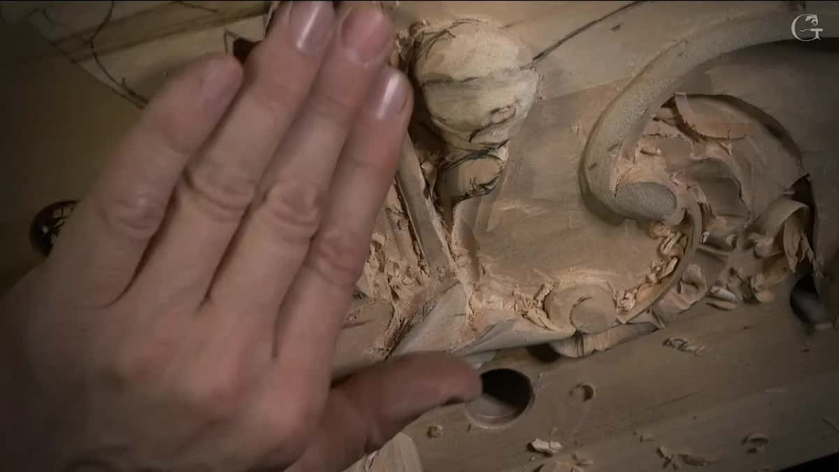 Fingertip pressed against the shaped surface while the rest of the hand rests on the carving
