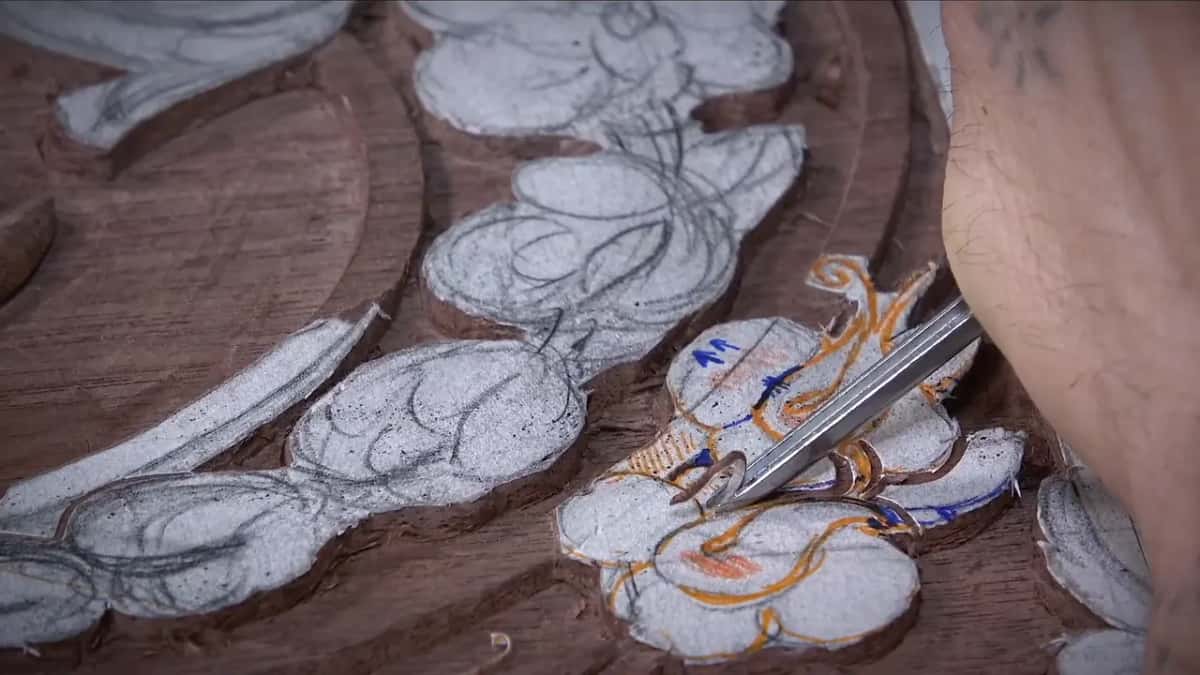 Fine twin bladed tool resting on a drawn leaf, a forearm crossing the top right corner, shavings everywhere