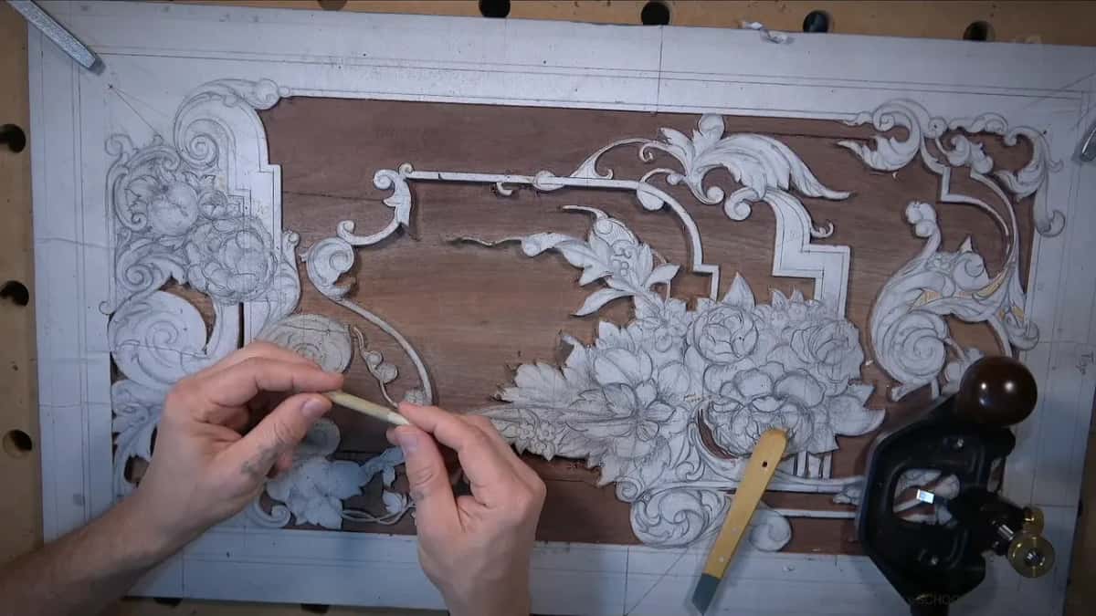 Two hands holding a thin pale rod of reed above the carved board, the plane parked over at right
