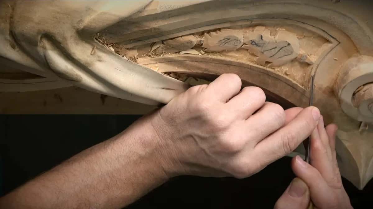 Close view of the thin blade entering the groove below the panel line, hands low against the wood