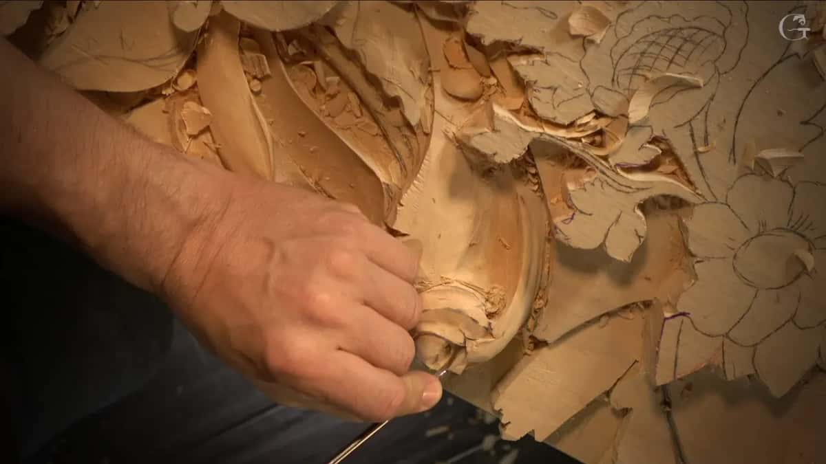 Part of the panel from above, a hand working at the scroll.