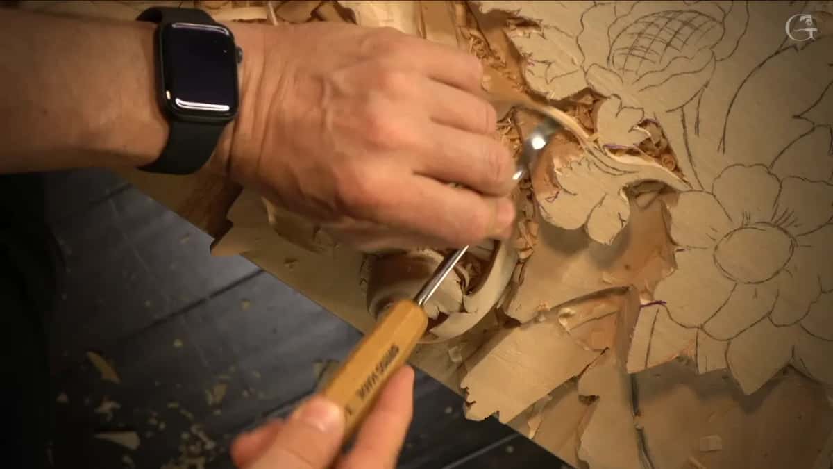 Wristwatch on, one hand steers a small tool into the scroll, with a pencil flower drawn to the right.