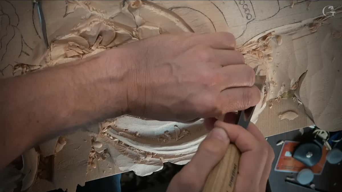 An arm reaches across the board as a pale handle comes up from below toward the scroll