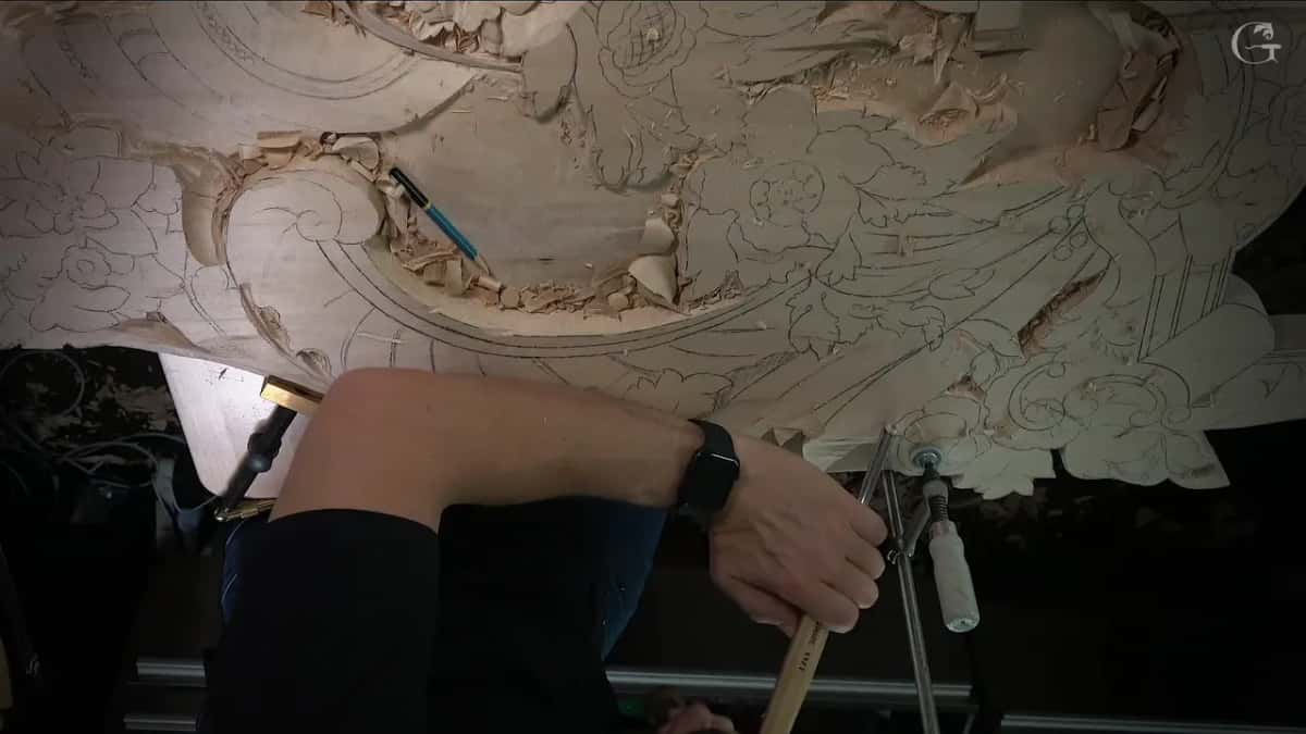 Blue pencil on the carving, arm resting while a tool works near the clamp